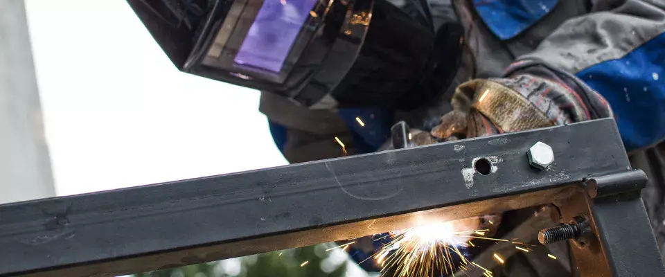 mężczyzna spawający metalową rurkę
